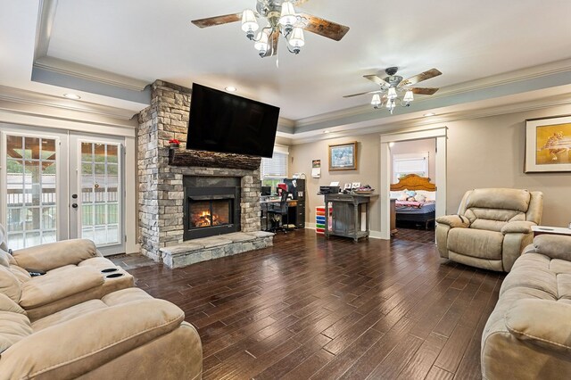 living area with plenty of natural light, crown molding, dark wood-type flooring, and a stone fireplace