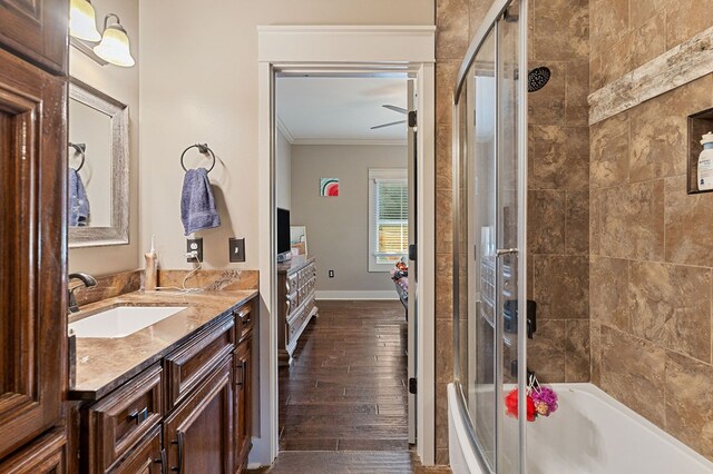 bathroom with tiled shower / bath, ornamental molding, vanity, wood finished floors, and baseboards