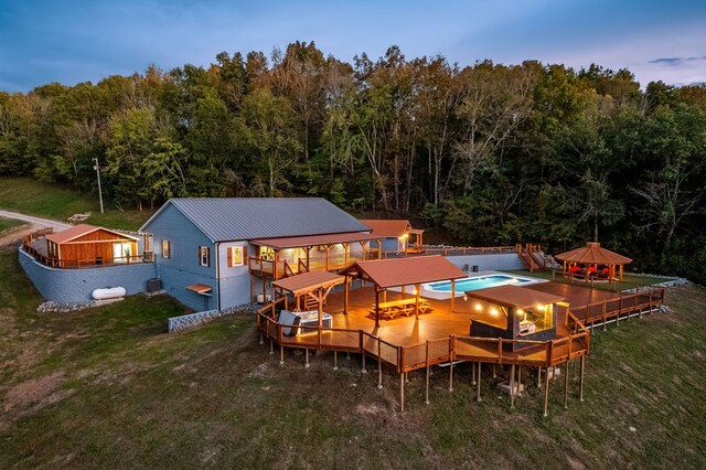 back of property at dusk featuring metal roof, a gazebo, and a view of trees