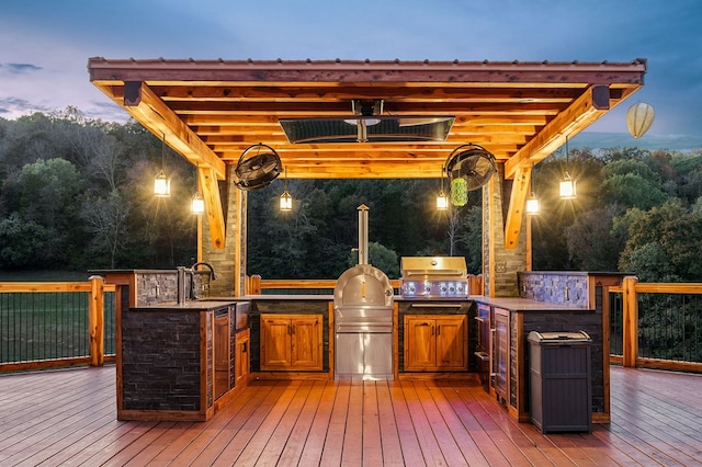 deck at dusk featuring a sink, outdoor dry bar, exterior kitchen, and area for grilling