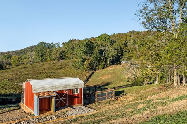 view of outbuilding with an outbuilding, a rural view, and a view of trees