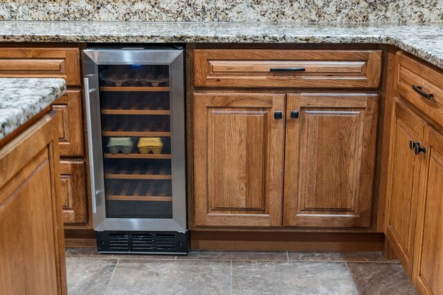 details with wine cooler, brown cabinets, and light stone countertops