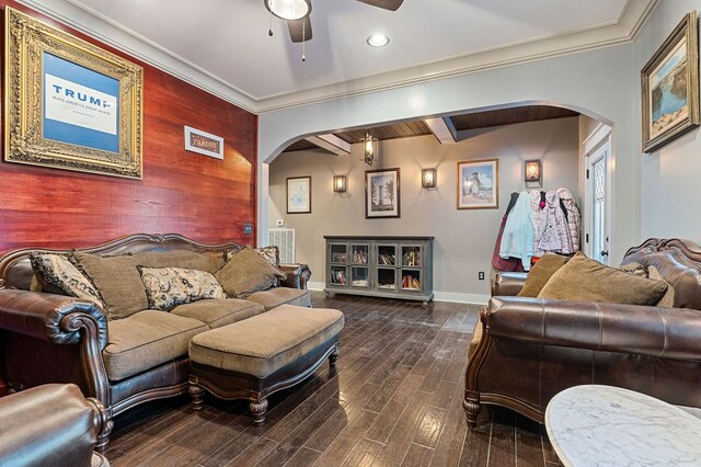 living area with arched walkways, an accent wall, ornamental molding, and wood finished floors