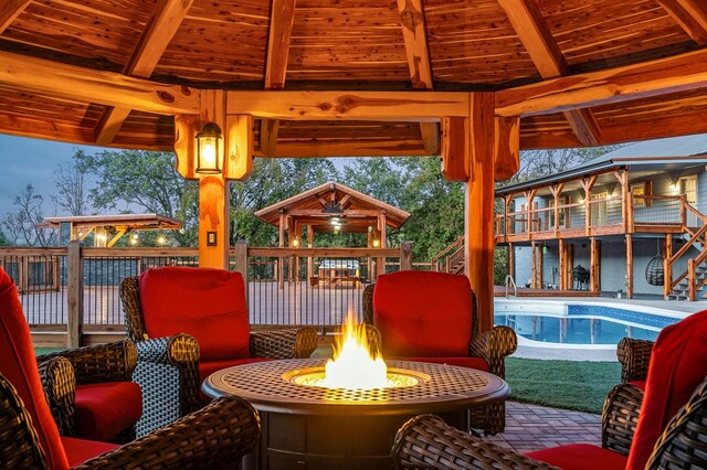 exterior space featuring a fire pit, a fenced in pool, and a gazebo