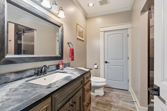 bathroom featuring visible vents, toilet, ornamental molding, vanity, and wood finished floors