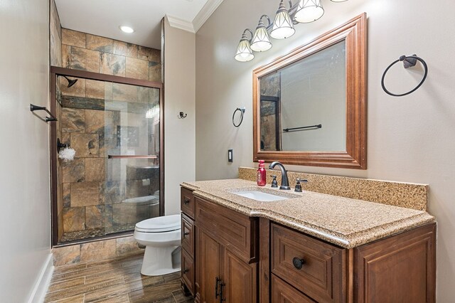 bathroom featuring wood finish floors, crown molding, toilet, a shower stall, and vanity