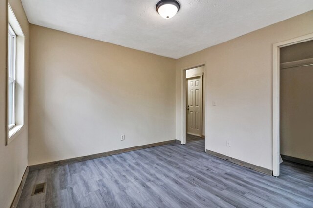 unfurnished bedroom featuring visible vents, dark wood finished floors, and baseboards