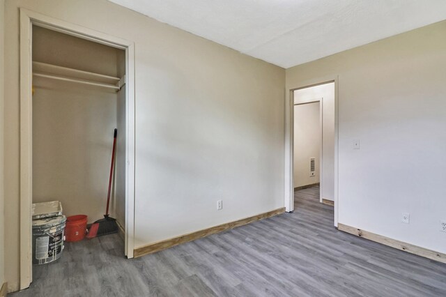 unfurnished bedroom featuring visible vents, baseboards, and wood finished floors