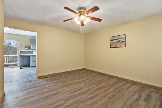 empty room with a ceiling fan, baseboards, and wood finished floors