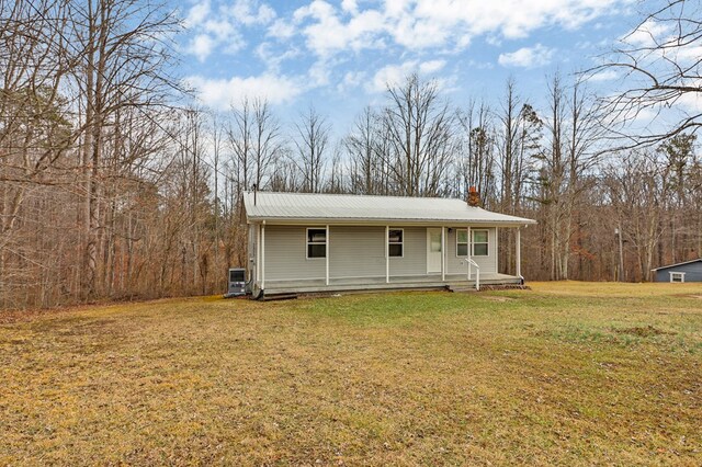 view of front of property with covered porch, metal roof, a chimney, and a front lawn