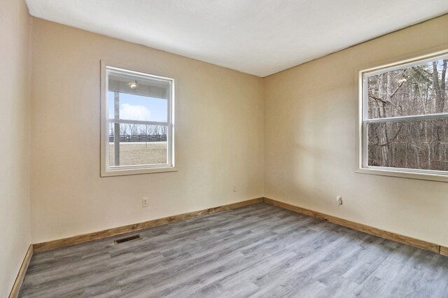 spare room featuring baseboards, visible vents, plenty of natural light, and light wood finished floors