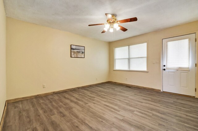 spare room featuring ceiling fan, a textured ceiling, baseboards, and wood finished floors