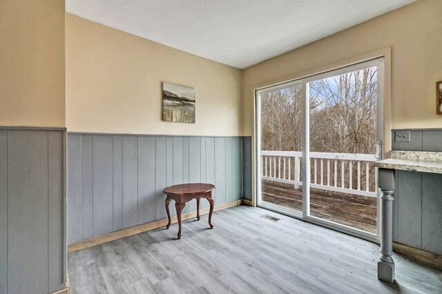 interior space featuring a wainscoted wall, visible vents, and light wood finished floors