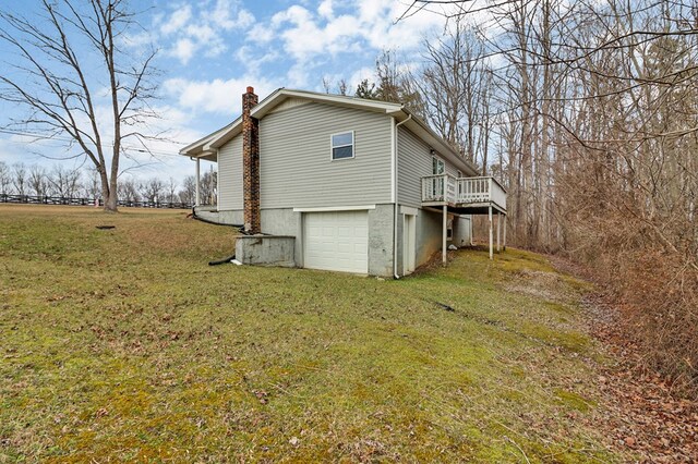 view of side of home featuring a deck, a garage, driveway, a yard, and a chimney