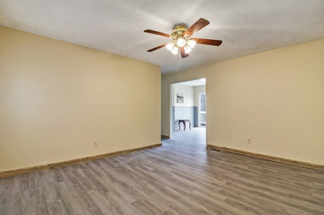 spare room featuring a ceiling fan, a textured ceiling, baseboards, and wood finished floors