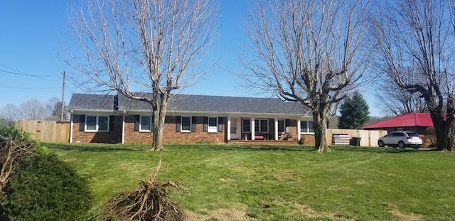 view of front of property featuring brick siding, fence, and a front yard