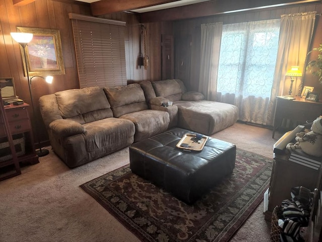 carpeted living area with beam ceiling and wooden walls