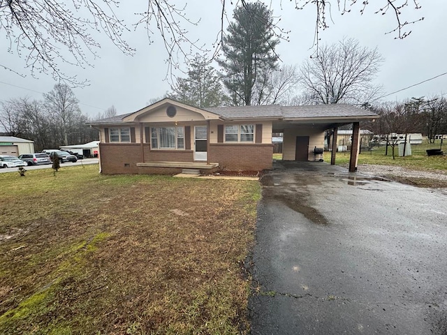 view of front of house featuring brick siding, aphalt driveway, a front yard, and an attached carport