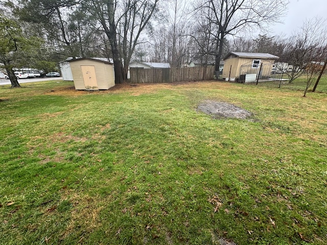 view of yard featuring fence, a storage unit, and an outdoor structure