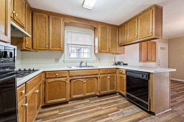 kitchen with a sink, black appliances, light countertops, and brown cabinets