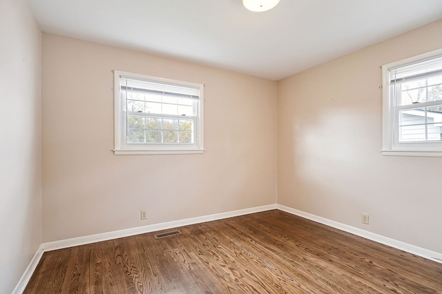 spare room with visible vents, dark wood finished floors, and baseboards