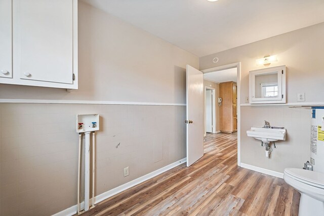 laundry area with laundry area, washer hookup, a sink, tile walls, and light wood-style floors