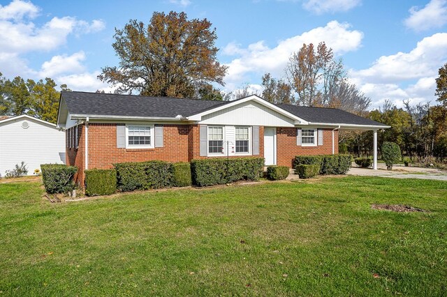 single story home featuring a carport, driveway, brick siding, and a front lawn