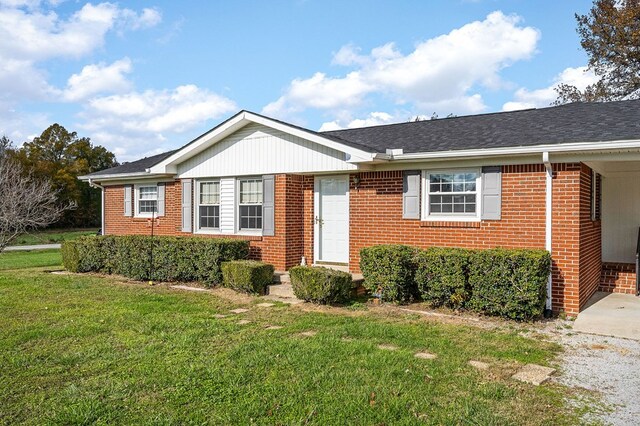 ranch-style home featuring roof with shingles, a front yard, and brick siding