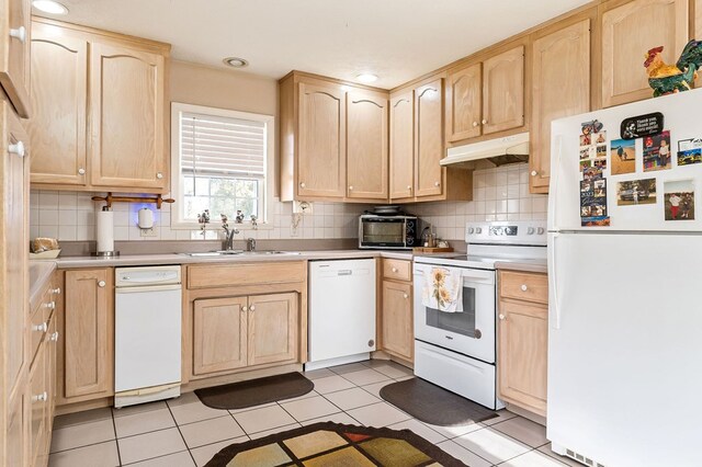 kitchen featuring under cabinet range hood, white appliances, a sink, light countertops, and light brown cabinetry