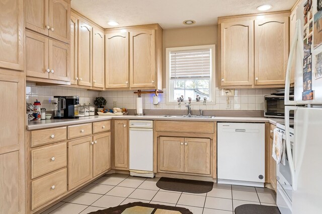 kitchen featuring light brown cabinets, light countertops, white appliances, and a sink