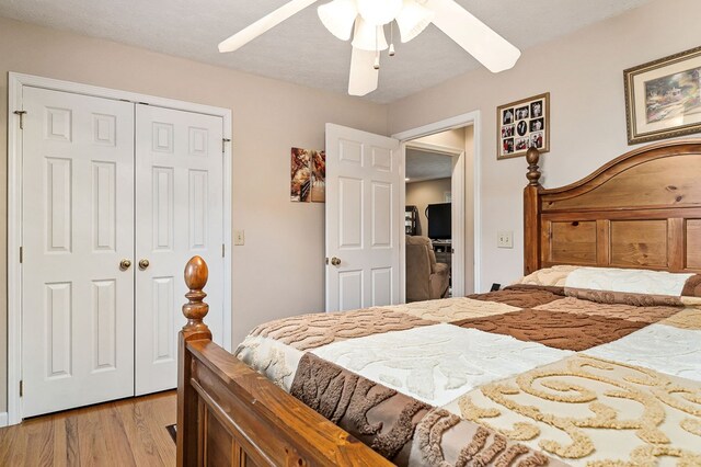 bedroom with light wood-style floors, a closet, a textured ceiling, and a ceiling fan