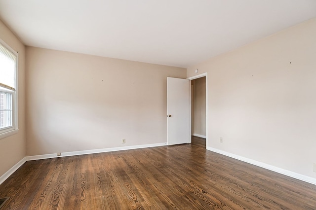 spare room with visible vents, baseboards, and dark wood finished floors