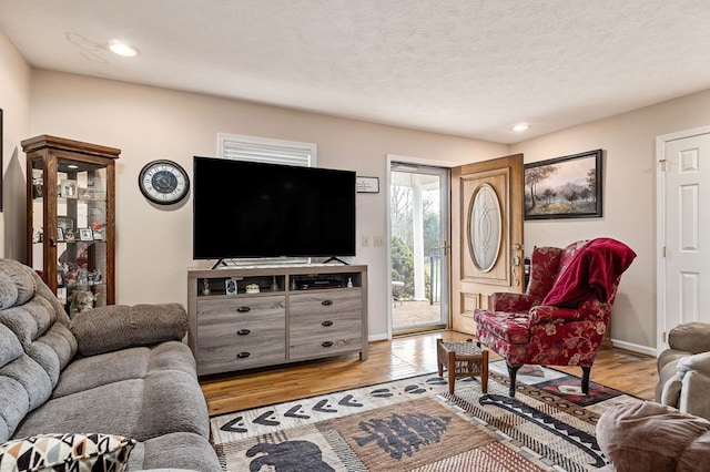 living area featuring a textured ceiling, recessed lighting, baseboards, and light wood-style floors