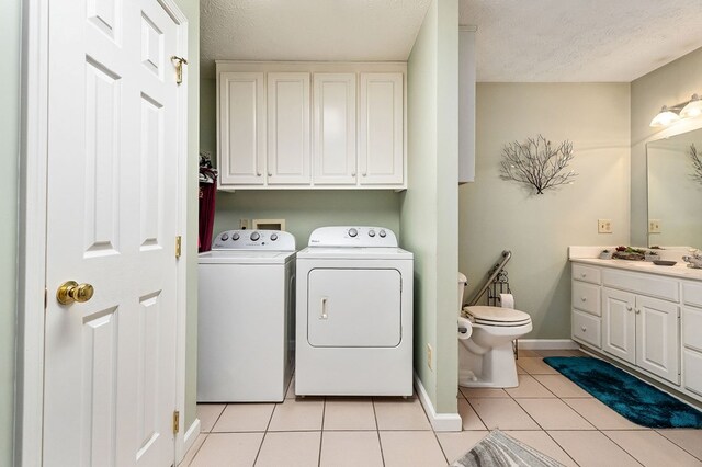 clothes washing area with light tile patterned floors, washing machine and dryer, baseboards, and a textured ceiling