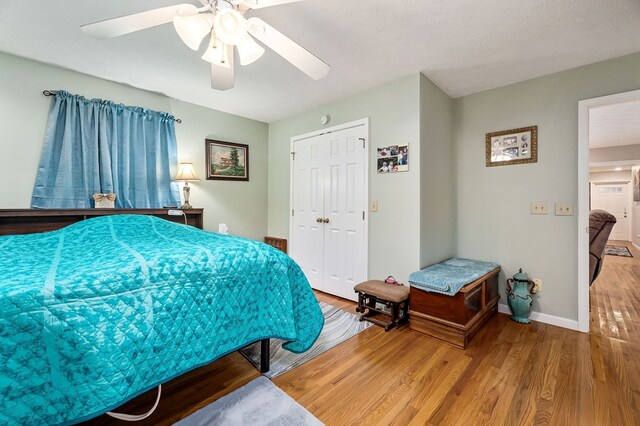 bedroom with a textured ceiling, wood finished floors, a ceiling fan, baseboards, and a closet