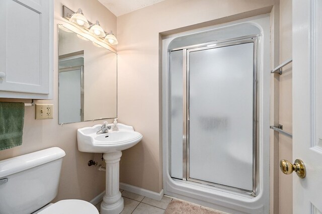 bathroom featuring tile patterned flooring, baseboards, a shower stall, and toilet