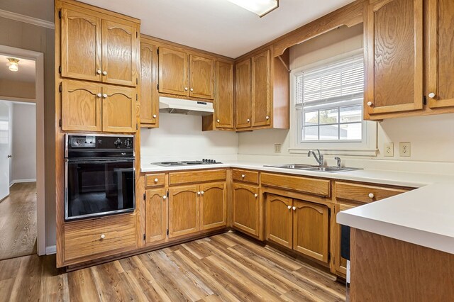 kitchen with brown cabinets, oven, light countertops, under cabinet range hood, and white gas cooktop