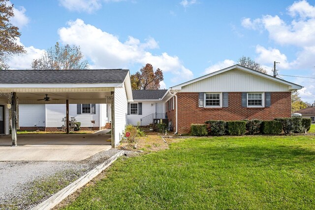 view of front of house with ceiling fan, brick siding, driveway, a carport, and a front lawn