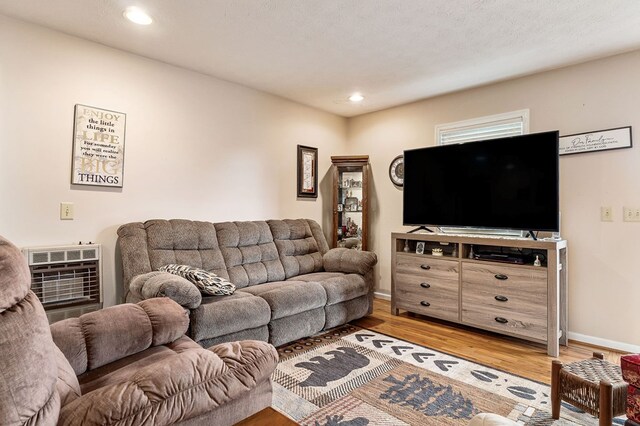 living area featuring heating unit, recessed lighting, a textured ceiling, wood finished floors, and baseboards