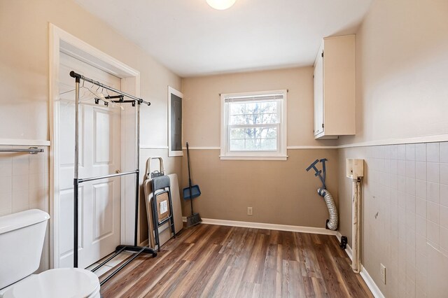 interior space with laundry area, wainscoting, dark wood-type flooring, heating unit, and tile walls