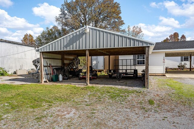 view of parking / parking lot featuring a detached carport, a pole building, and driveway