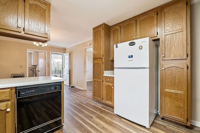 kitchen featuring black dishwasher, light countertops, freestanding refrigerator, and brown cabinets