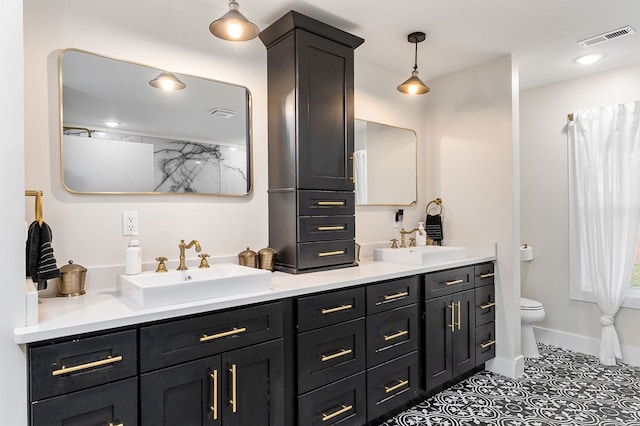 full bathroom with visible vents, a sink, toilet, and double vanity