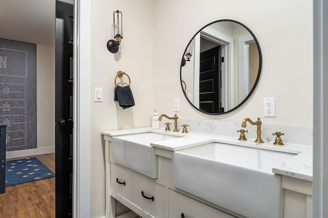 full bathroom featuring double vanity, baseboards, a sink, and wood finished floors