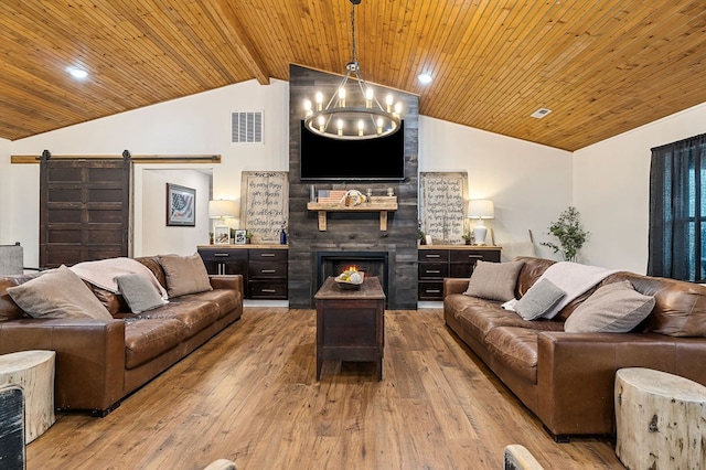 living area featuring a large fireplace, a barn door, wood ceiling, and visible vents