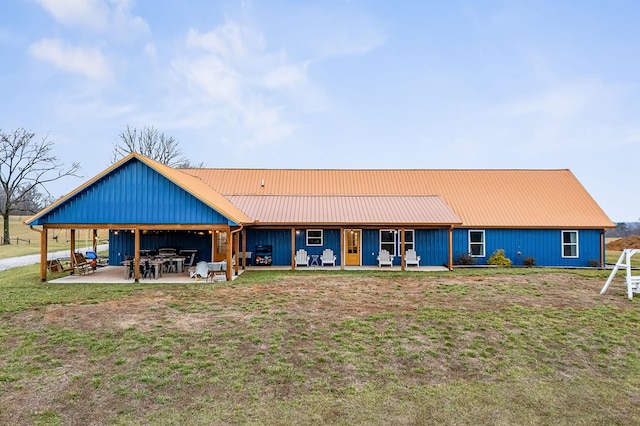 rear view of house featuring metal roof, a patio, and a yard