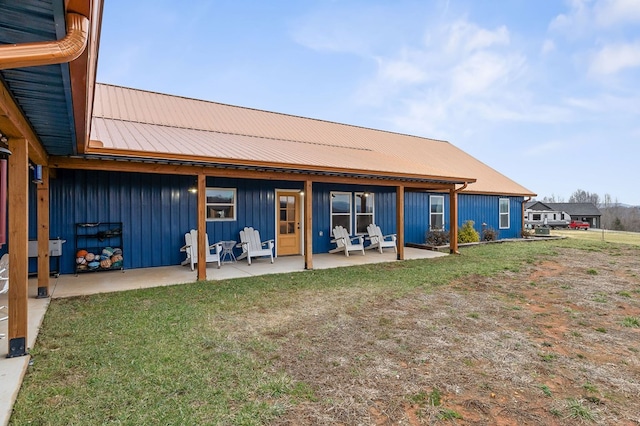 back of property featuring a patio area, metal roof, board and batten siding, and a yard