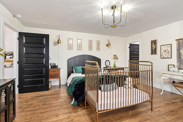 bedroom featuring baseboards, an inviting chandelier, and wood finished floors