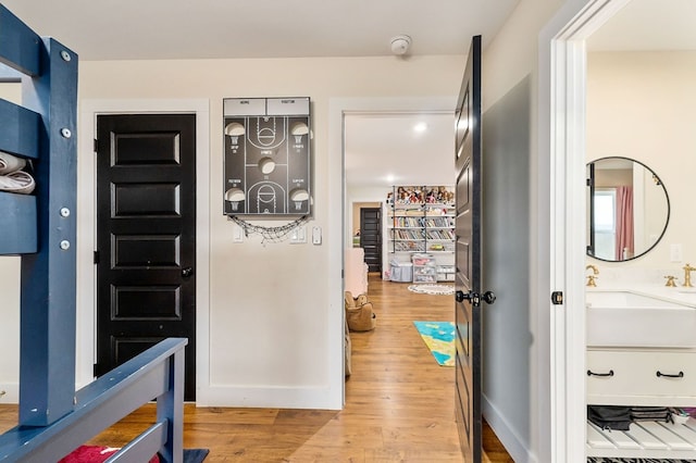 hallway with a sink, baseboards, and wood finished floors