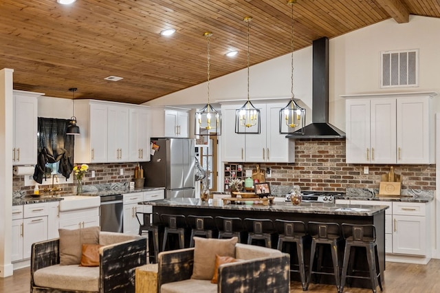 kitchen featuring wall chimney exhaust hood, a breakfast bar area, and visible vents